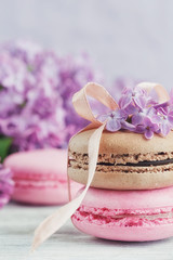 Fototapeta na wymiar Cup of black coffee, lilac flowers and sweet pastel french macar