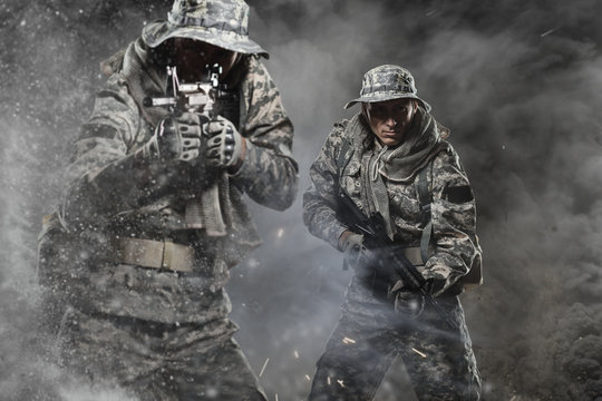 Two Special forces soldiers men holding a machine gun on dark background