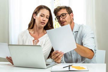 Male and female colleagues discussing document at office