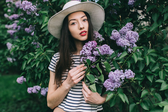 Portrait of stylish girl hipster on the street among a blossoming lilac