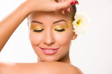 Fototapeta na wymiar Gold make up. Brown sleek hair beautiful woman with white flower