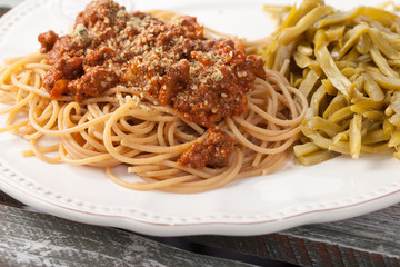 Whole wheat spaghetti with French style cut green beans on a weathered barn wood table