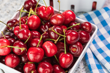 Colanders with red organic cherries on kitchen table.
