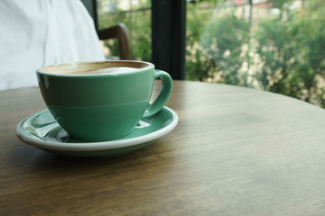 Obraz premium Green coffee cup on a wooden table