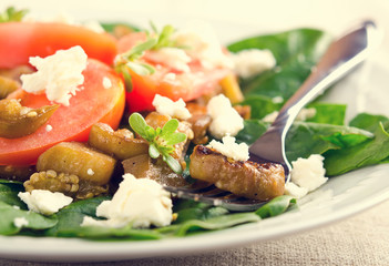 Eggplant salad with tomatoes, feta cheese, spinach and greens