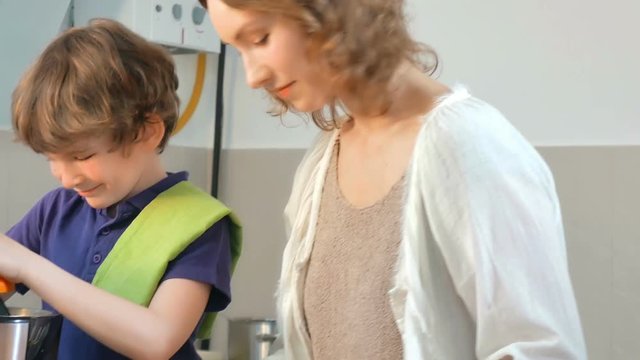Young Caucasian Mother and Child Homemade Fresh Orange Juice in Kitchen with Electric Juicer