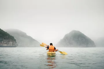 Foto op Canvas Couple paddling the kayak in mist weather © gilitukha