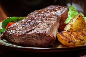 Portions of grilled beef steak with grilled potatoes and paprika