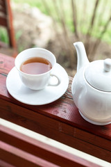 Cup of black tea and kettle on veranda