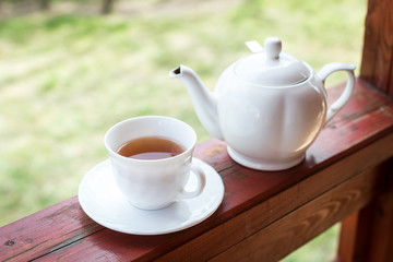 Cup of black tea and kettle on veranda