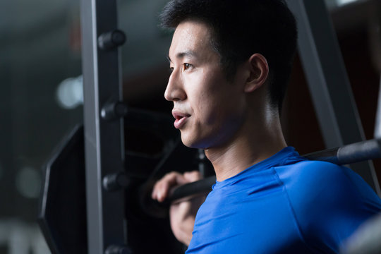 Young Asian Man Working Out In Modern Gym