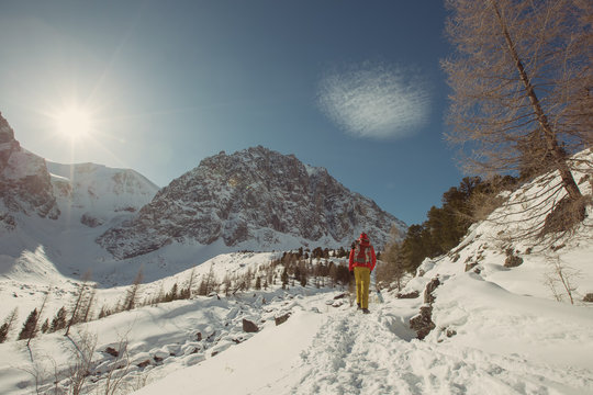Tourist walking in winter snow high mountains. Sport outdoor, beautiful mountain top, cloud and sun rays in blue  sky