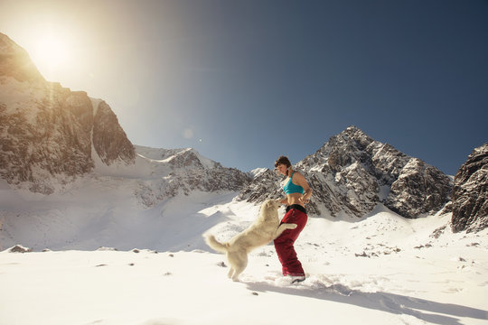 Woman and Dog playing together outdoor in Snow Mountains landscape
