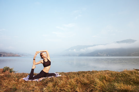 Young Girl doing morning yoga exercise on mountain lake. Fitness sport outdoor