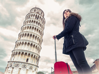 tourist woman with suitcase in Italy next to the Tower of Pisa