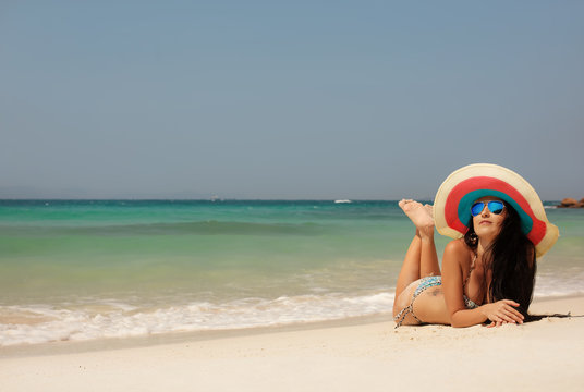 Young girl in big hat lung on sea beach. Summer, sun, vacation and travel. Enjoy of Freedom