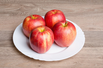 Fototapeta na wymiar Red apples on white plate and wood table