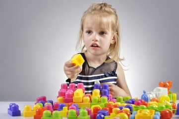 Fototapeta na wymiar Portrait of beautiful little girl playing with plastic toy cubes