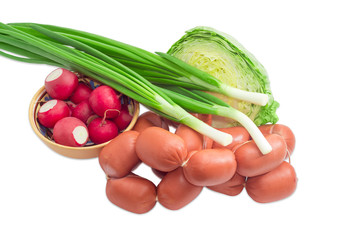 Bunch of uncooked wieners and fresh spring vegetables