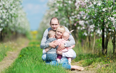 Naklejka na ściany i meble Family among the blossoming apple-trees.