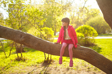 little girl sitting on a tree in the Park. child plays outdoors