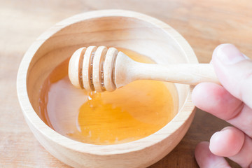 Hand on honey dipper from wooden cup