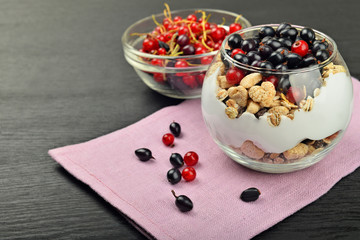 full bowl of muesli with berries near the bowl with berries on a napkin on a dark wooden background