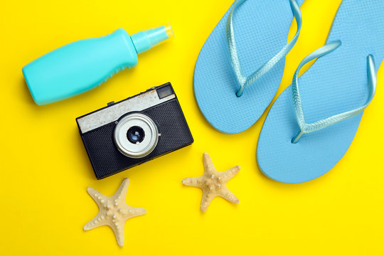 beach shoes with sunglasses and a camera on a yellow background