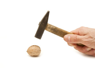 The hand with a hammer breaks walnuts