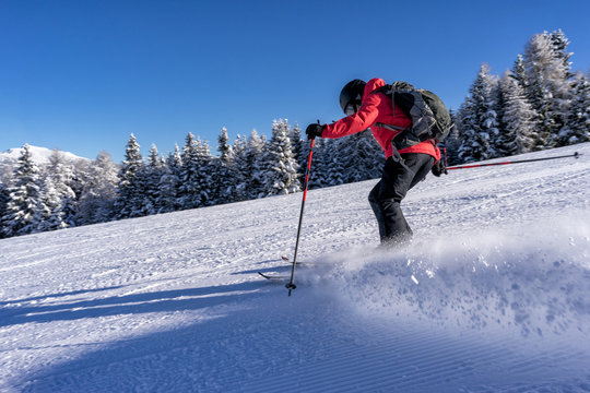 Female skier dressed in red jacket enjoys slopes in Italy.