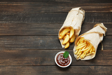 Fries and potato wedges wrapped takeaway at wood
