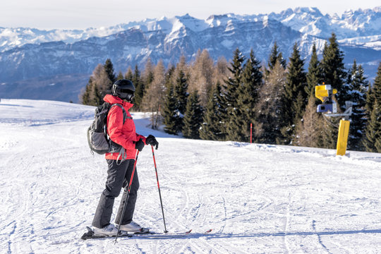 Female skier enjoys view on italien slopes with beautiful mountains in distance.