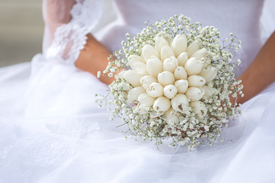 The bride holds a beautiful wedding bouquet of white flowers.