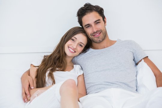 Portrait of happy couple sitting on bed