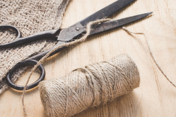 Old scissors and skein jute twine on a wooden background, selective focus, rustic style.