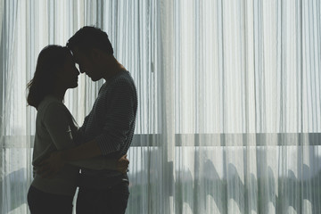 Silhouette of couple kissing in dark room