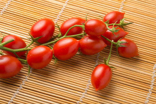 Grappolo di pomodorini rossi maturi san Marzano su una stuoia di bamb&ugrave;