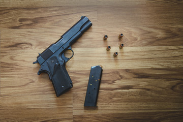 Top view of Pistol semi-automatic .45 caliber with magazine and bullet on the wooden table