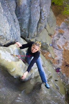 The girl climbs on the rock.