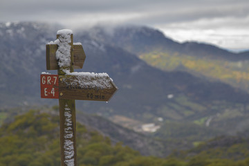 Señalización sendero con nieve y sierras al fondo en el P.N. Sierra de Grazalema.