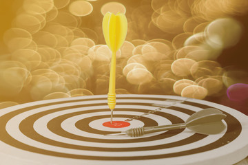 darts arrows in the target center on yellow bokeh
