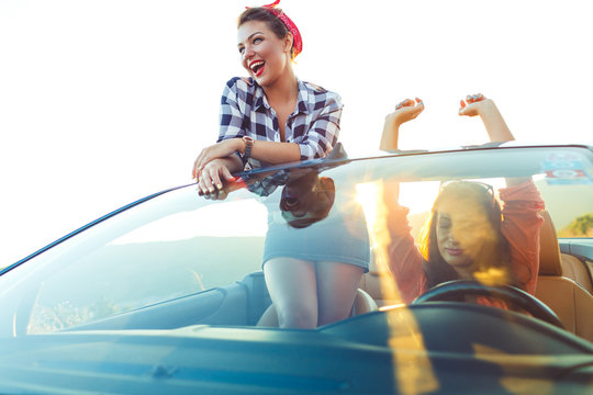 Two young happy girls having fun in the cabriolet outdoors