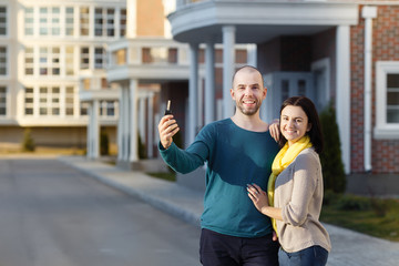 Young happy couple in front of their new home showing off their house keys
