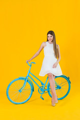 Beautiful young woman posing seated on a blue bicycle
