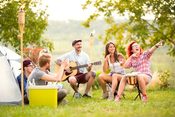 Smiling girls show something in distance in campground - obrazy, fototapety, plakaty