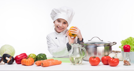 little girl-cook by table with vegetables