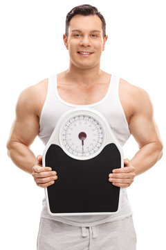 Muscular man holding a weight scale