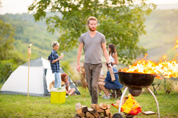 Man put firewood in flared up grill