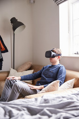 Fototapeta premium Man Sitting On Sofa At Home Wearing Virtual Reality Headset