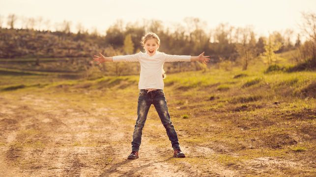 cute little girl standing with hands to sides on a road